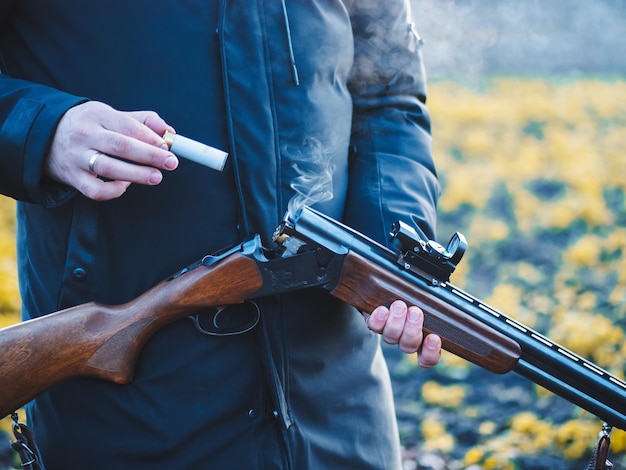 Foto sección media de un hombre retirando una bala de una escopeta mientras está de pie al aire libre