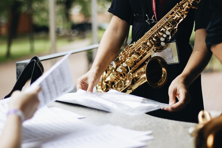 Foto sección media de un hombre con saxofón sosteniendo papel mientras está de pie junto a la mesa
