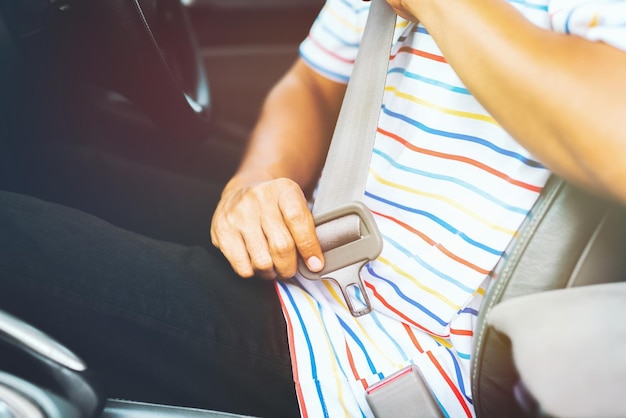 Sección media de un hombre sosteniendo el cinturón de seguridad mientras está sentado en un coche