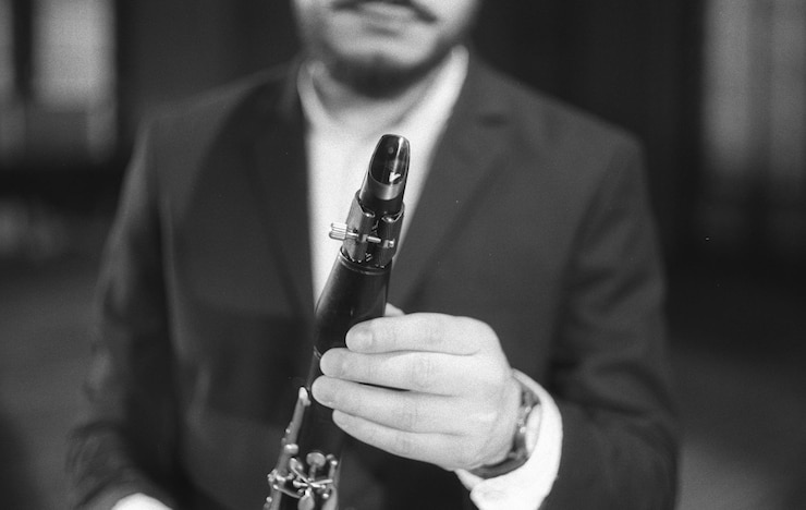 Foto sección media de un hombre sosteniendo un clarinete mientras está de pie en el estudio