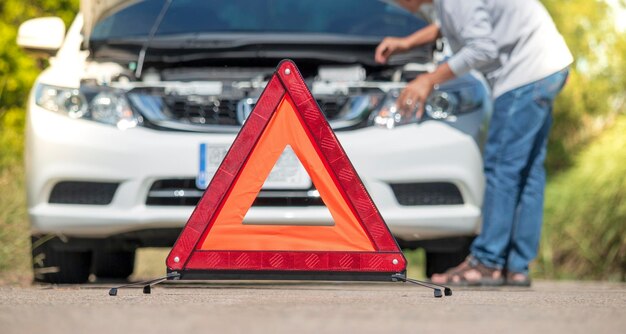 Foto sección media de un hombre sosteniendo un coche rojo en la carretera