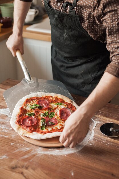 Foto sección media de un hombre sosteniendo helado en la mesa en la cocina