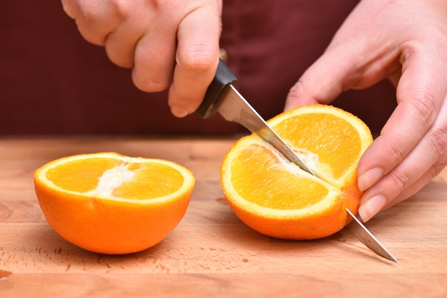 Sección media de un hombre sosteniendo jugo de naranja en la tabla de cortar
