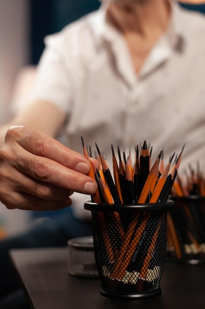 Foto sección media de un hombre sosteniendo lápices en la mesa