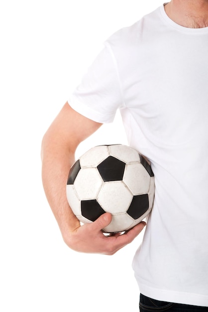 Foto sección media de un hombre sosteniendo una pelota de fútbol mientras está de pie contra un fondo blanco