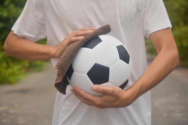 Foto sección media de un hombre sosteniendo la pelota mientras está de pie en el campo de fútbol