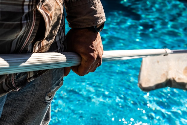 Foto sección media de un hombre sosteniendo una red mientras está de pie junto a la piscina