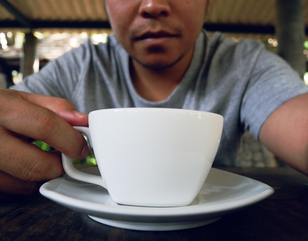 Foto sección media de un hombre sosteniendo una taza de café en una mesa en una cafetería