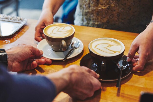 Foto sección media de un hombre sosteniendo una taza de café en la mesa