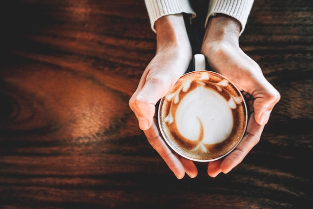Sección media de un hombre sosteniendo una taza de café en la mesa