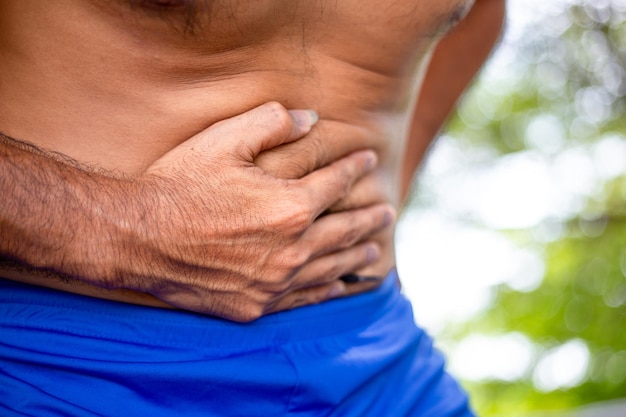 Foto sección media del hombre tocando el abdomen con dolor