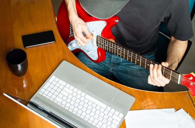 Foto sección media de un hombre tocando la guitarra en casa