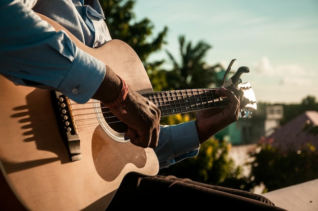 Sección media de un hombre tocando la guitarra en un día soleado
