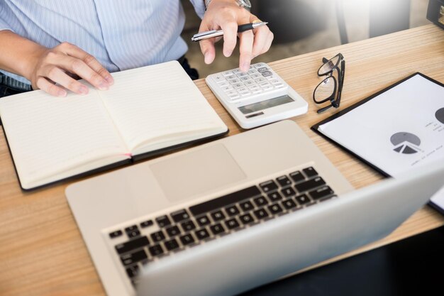 Foto sección media de un hombre usando una calculadora mientras trabaja en un escritorio