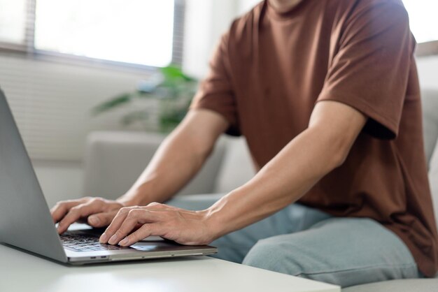 Sección media de un hombre usando una computadora portátil en casa