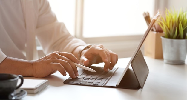 Sección media de un hombre usando una computadora portátil en la mesa en casa