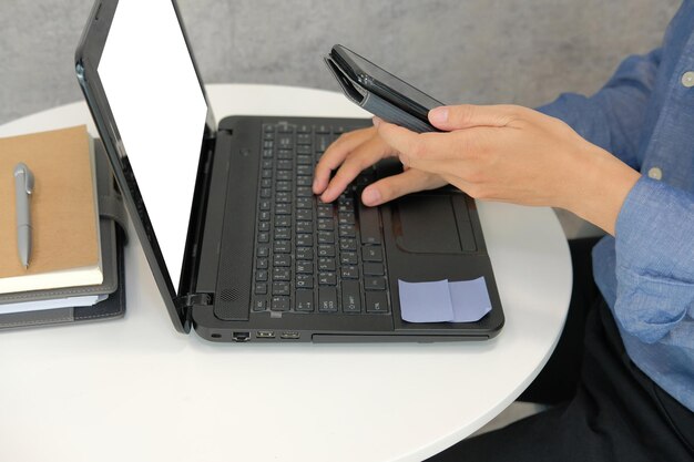 Sección media de un hombre usando una computadora portátil en la mesa