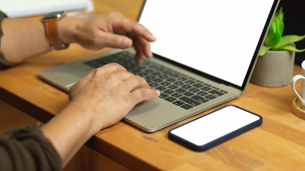 Sección media de un hombre usando una computadora portátil en la mesa