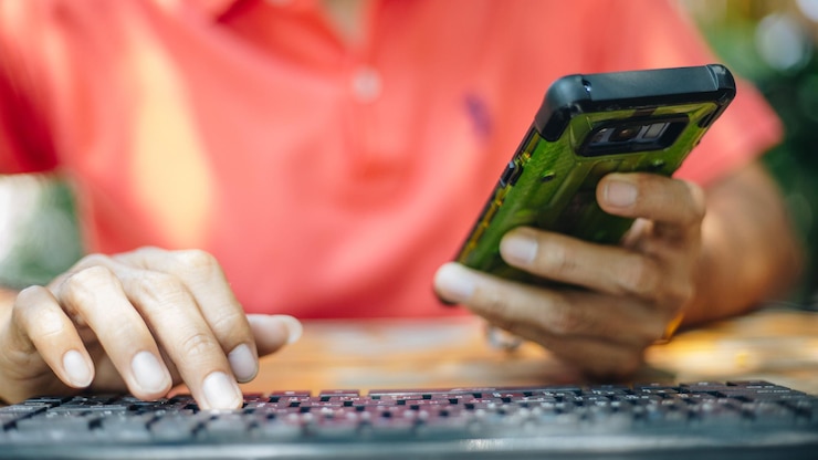 Foto sección media de un hombre usando teléfono móvil y computadora en la mesa