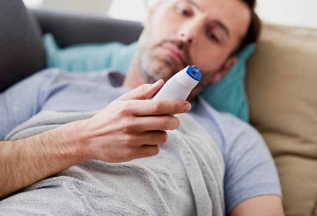Sección media de un hombre usando el teléfono móvil mientras está sentado en el sofá