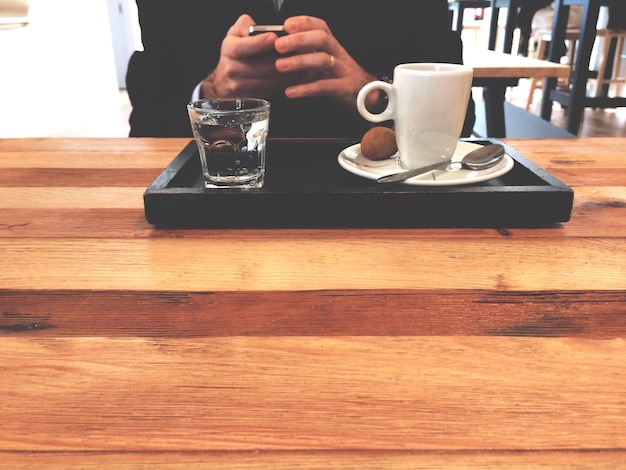 Foto sección media de un hombre usando un teléfono móvil mientras está sentado en una mesa en una cafetería