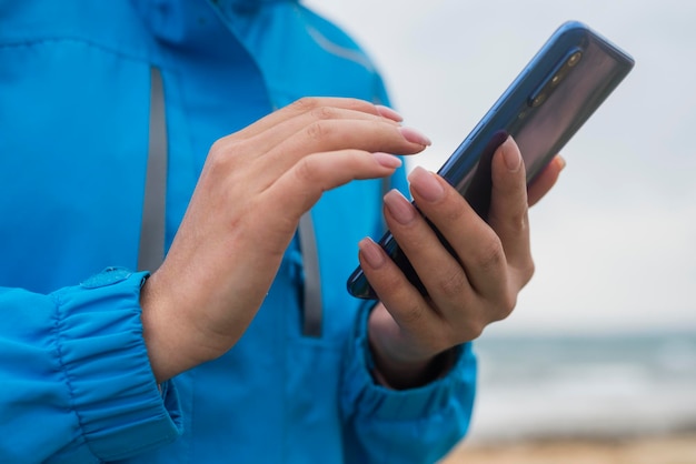 Sección media de un hombre usando un teléfono móvil en la playa