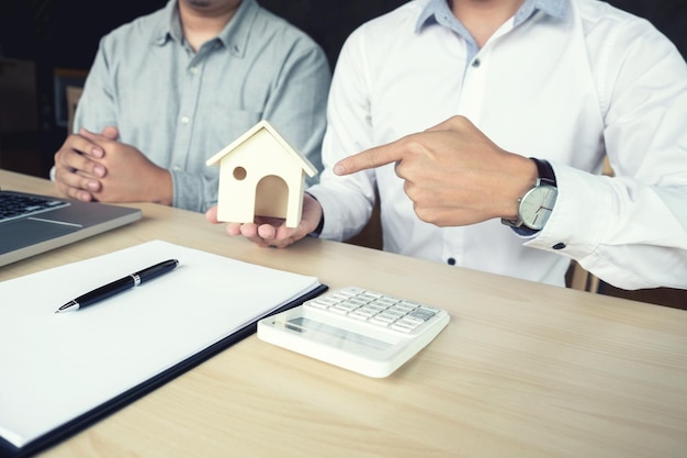 Foto sección media de hombres de negocios con una casa modelo sentados en el escritorio