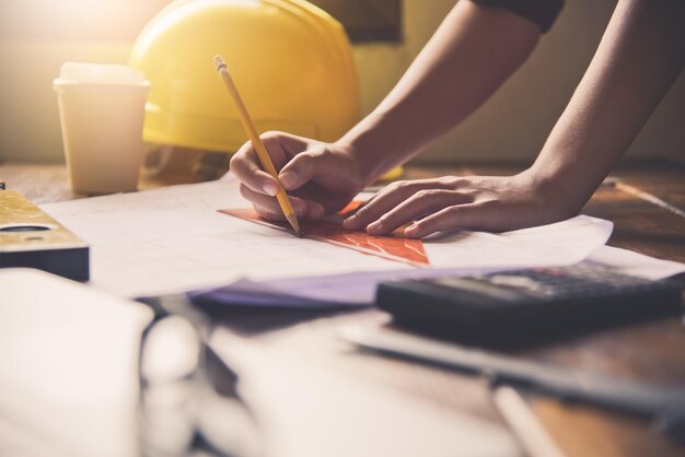 Sección media de un ingeniero trabajando en un plano en la mesa de la oficina