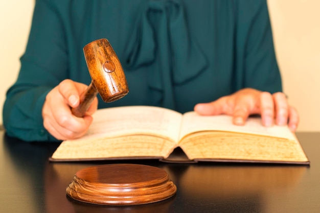 Foto sección media del juez con el libro sosteniendo el martillo en el escritorio en la sala del tribunal