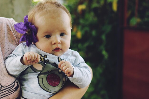 Foto sección media de la madre sosteniendo a su linda hija con una flor púrpura