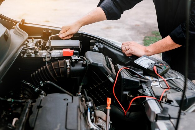 Sección media de un mecánico reparando el motor de un automóvil mientras está de pie en el garaje