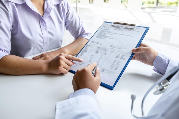 Foto sección media del médico discutiendo con el paciente en la mesa en el hospital