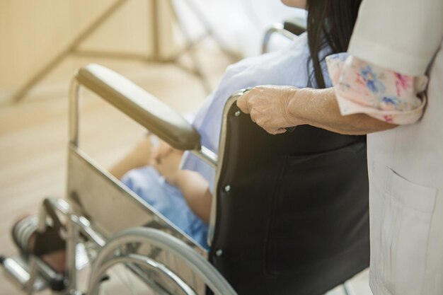 Foto sección media de un médico empujando una silla de ruedas con una mujer