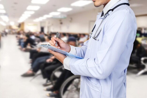 Foto sección media del médico escribiendo en el clipboard mientras está de pie en el hospital