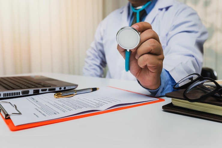 Foto sección media del médico con el estetoscopio en la mesa en la clínica