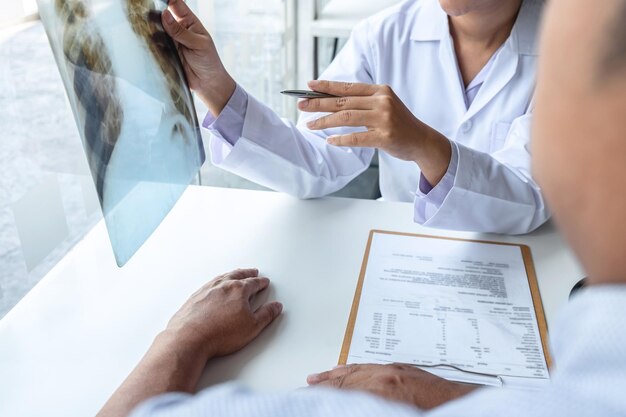 Foto sección media del médico explicando los rayos x al paciente en la mesa en el hospital
