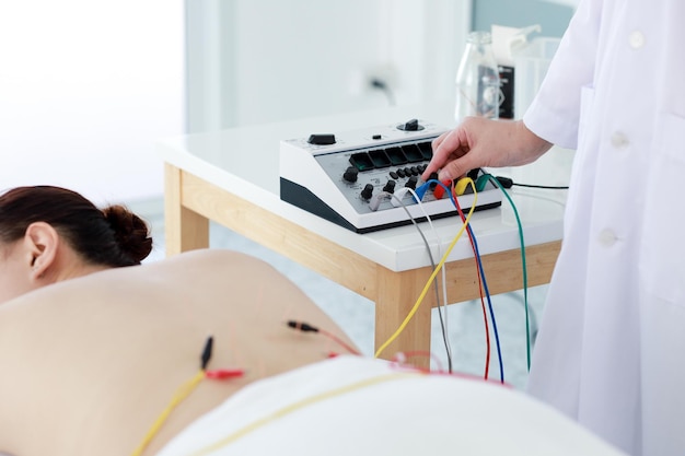 Foto sección media de un médico que trata a un paciente con terapia de acupuntura en una clínica