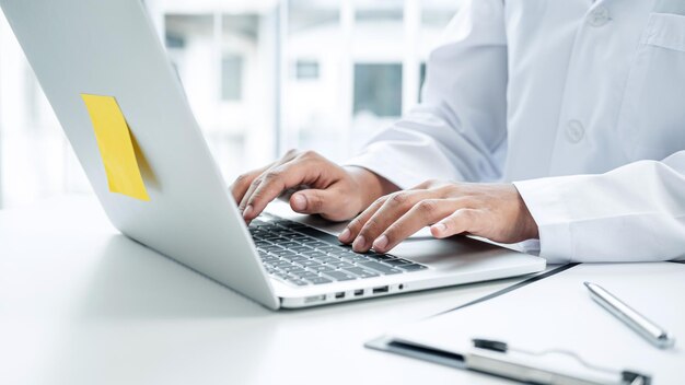 Sección media del médico usando la computadora portátil en la clínica