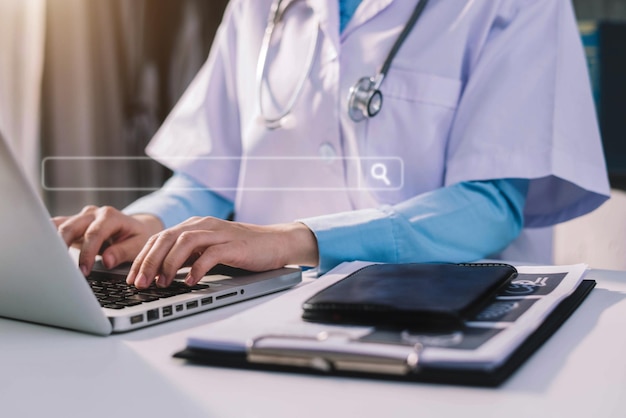 Sección media del médico usando una computadora portátil en la mesa de la clínica