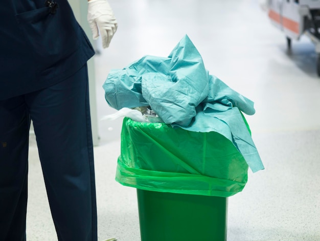 Sección media de médicos por la basura en un contenedor en el hospital
