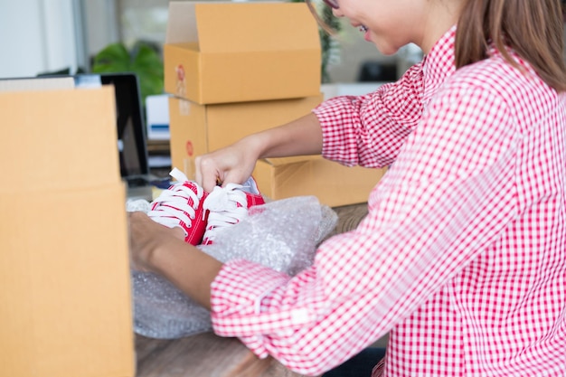 Foto sección media de una mujer abriendo la caja de zapatos en casa