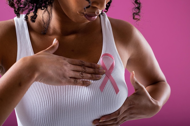 Foto sección media de una mujer adulta media afroamericana con una cinta rosa de concientización sobre el cáncer de mama en el pecho