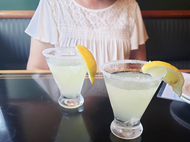 Foto sección media de una mujer con una bebida en la mesa en un restaurante