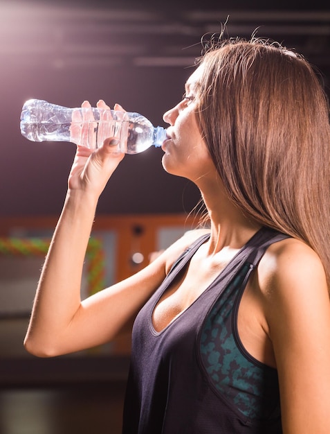 Sección media de una mujer bebiendo agua de botella