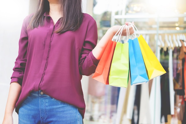 Sección media de una mujer con bolsas de compras de pie al aire libre