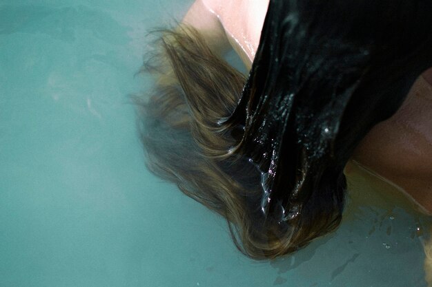 Sección media de una mujer con cabello largo nadando en la piscina