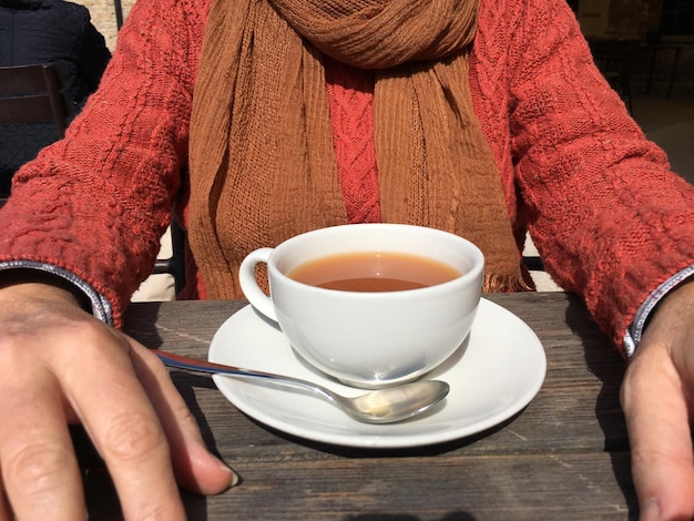 Foto sección media de una mujer con café sentada en un día soleado