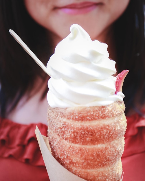 Foto sección media de una mujer comiendo un cono de helado