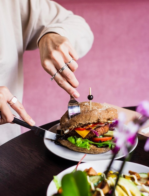 Sección media de una mujer comiendo una hamburguesa en la mesa