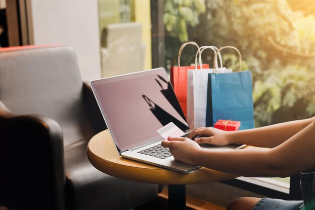 Sección media de una mujer comprando en línea mientras está sentada en la mesa